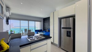 A modern kitchen with a large island, a stainless steel refrigerator, and a view of the ocean. - Beautiful Malecon and Beyond 514 Torre eMe (Mazatlán)