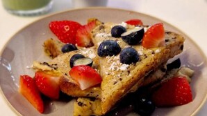 Une assiette de pain perdu, garnie de fraises et de myrtilles.