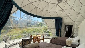 Alojamiento con carpa que incluye dos camas, una mesa, sillas, un ventilador y vistas al exterior.