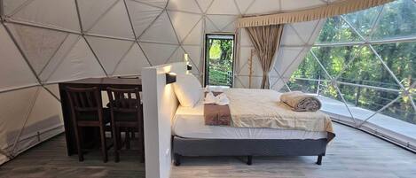 A tented room with a bed, a desk, and a chair.