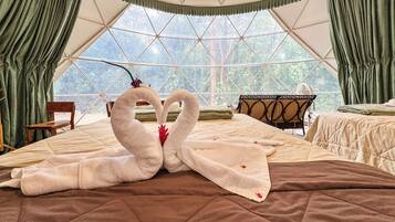 Una habitación con cama, una silla, un ventilador y vistas amplias por un ventanal.