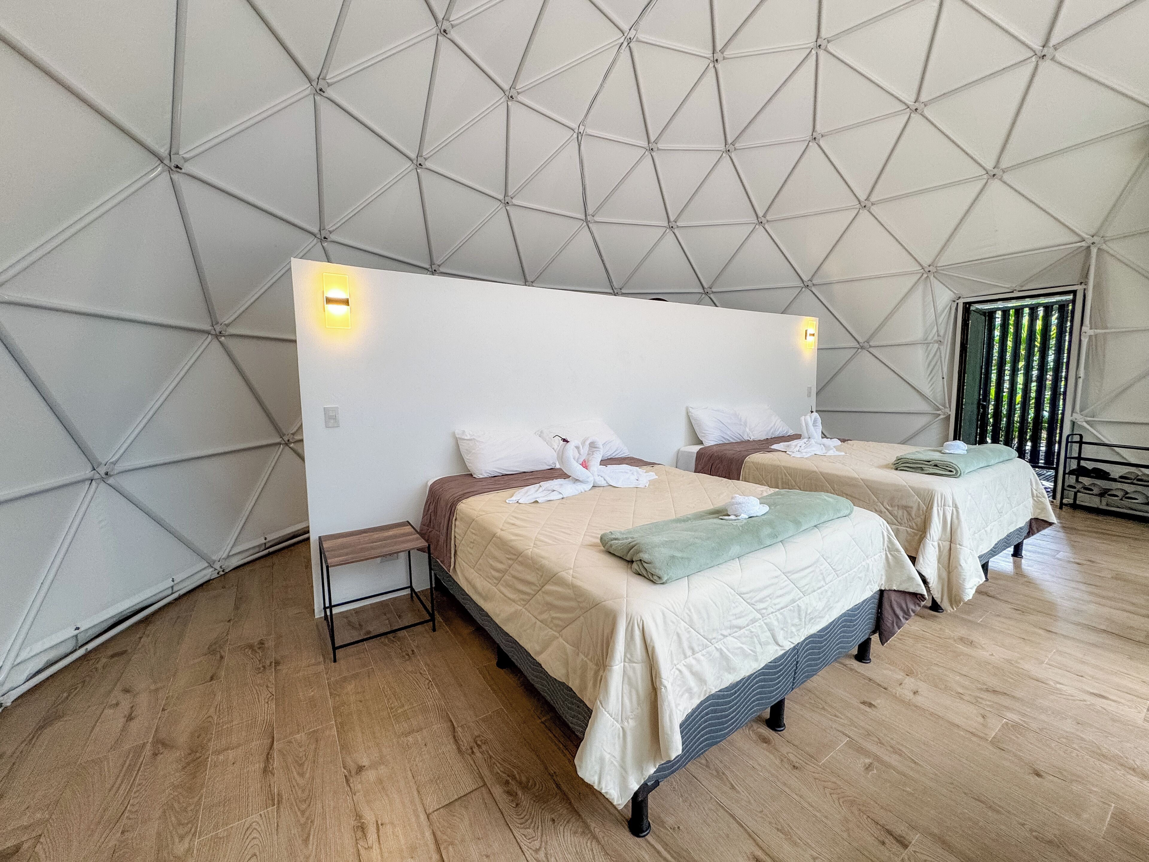A tent-style room with two beds, wooden flooring, and a geometric ceiling design.