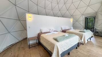 A tent-style room with two beds, wooden flooring, and a geometric ceiling design.