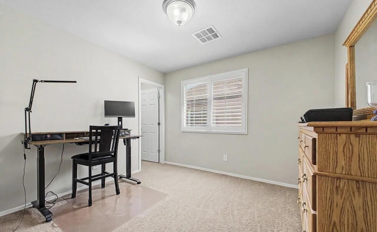 A room with a desk, chair, computer, and a dresser.