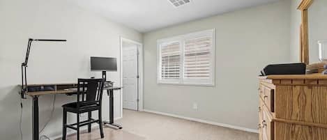 A room with a desk, chair, computer, and a dresser.