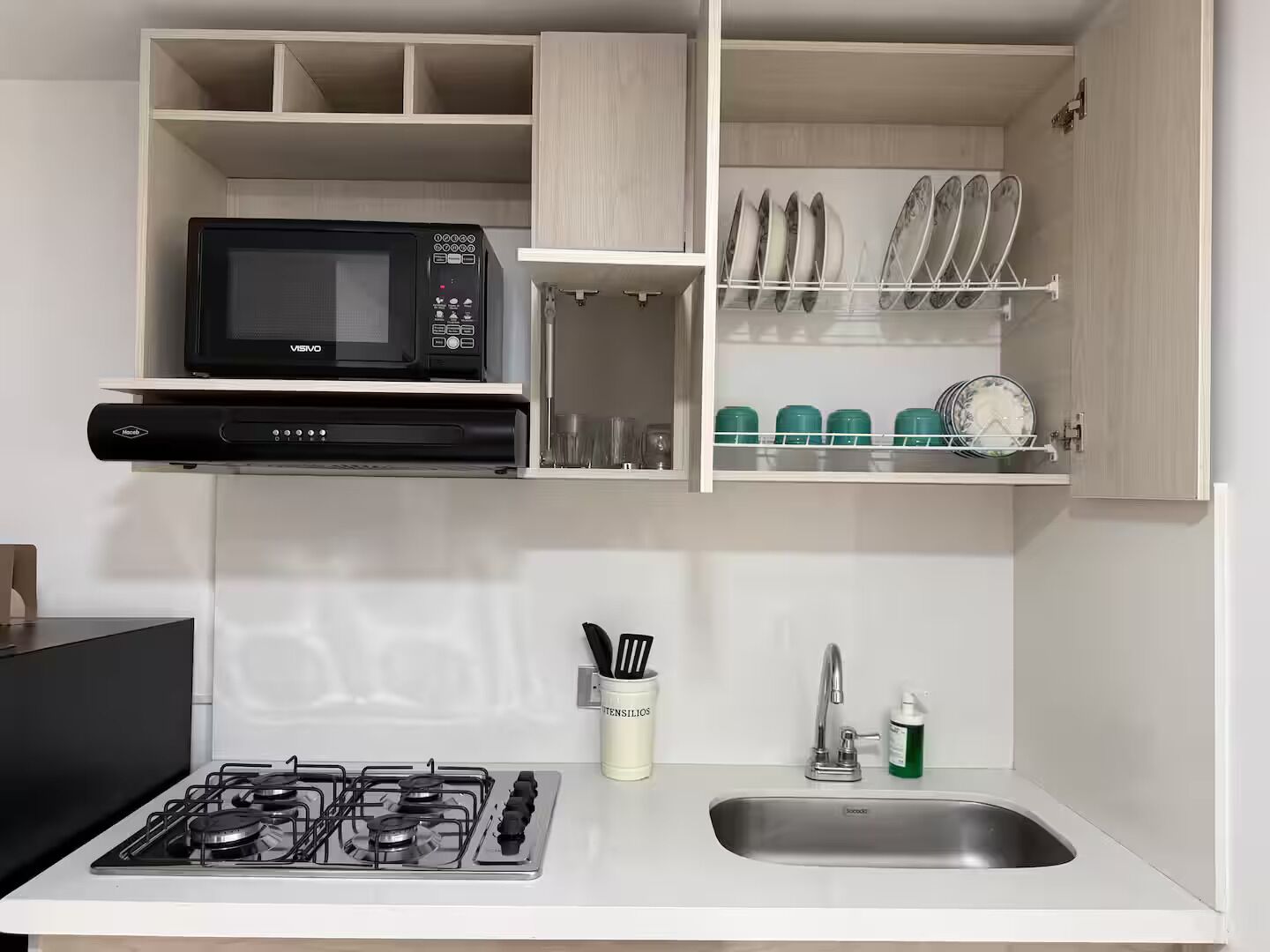 Una cocina con microondas, estufa y escurreplatos.