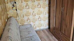 Ein Zimmer mit einem gemusterten Wand, einem Holzschrank und einem Sofa.