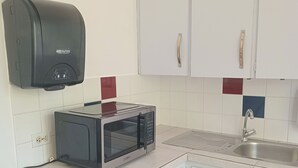 A compact kitchen with a microwave, a paper towel dispenser, and a sink. - Group Accommodation WEAVING MILL ARUBA (Oranjestad)