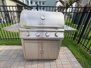 Ein Edelstahl-Grill für den Außenbereich mit vier Brennern, einem integrierten Thermometer und einer Seitenablagefläche.