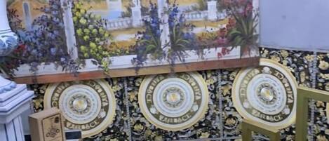 A room with a tiled wall, a decorative railing, and a painting of a fountain.
