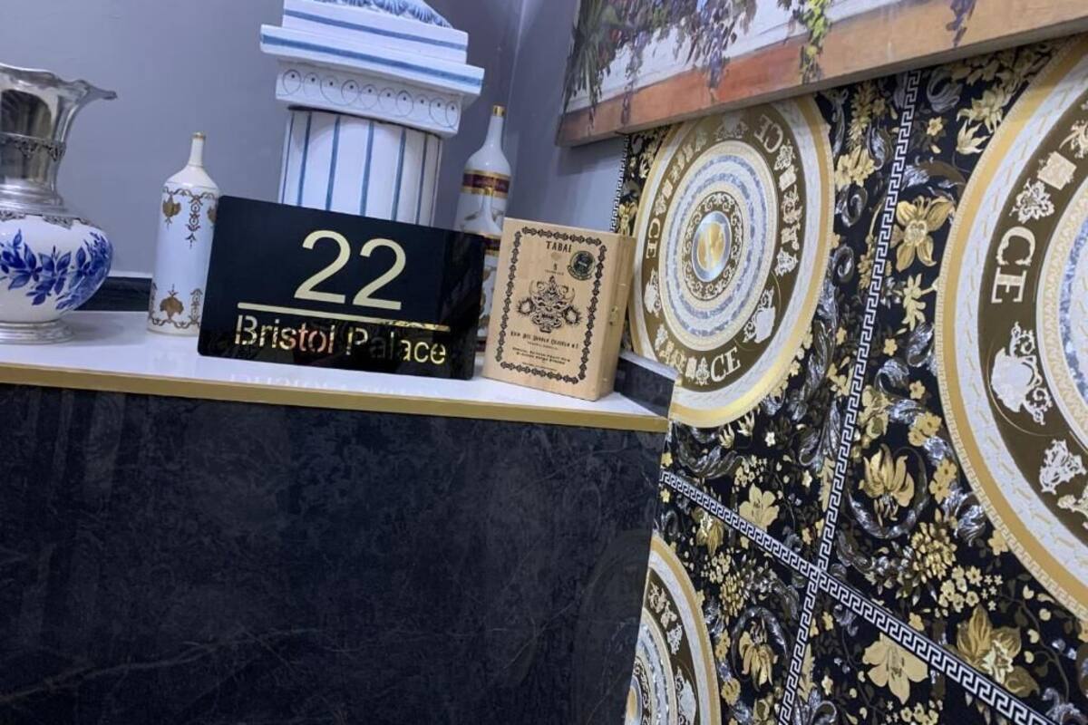 A room number sign, a decorative vase, and a patterned wall.