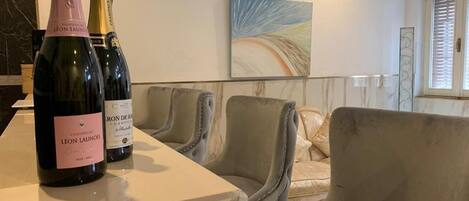 Una habitación con encimera de mármol, dos botellas de champán y un sofá color beige.