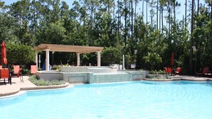 Piscina com área de estar coberta e cadeiras vermelhas.