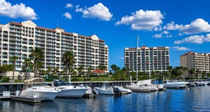 A marina with several boats docked, surrounded by multi-story hotels with balconies and a clear blue sky. - Couples King Suite at Barefoot Resort / Private Entrance, Resort Pool, Marina (N Myrtle Beach)