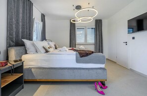 Et moderne soveværelse med seng, sengeborde, et klædeskab og et fjernsyn.