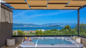A hot tub with a view of a lake and mountains.
