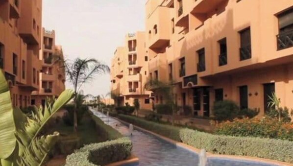 A residential building with multiple balconies, a central pathway, and surrounding greenery. - Premium Village Marrakech (Marrakesh)