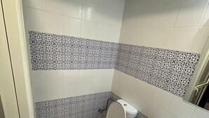 Een badkamer met toilet, wastafel en tegelvloer met patroon.