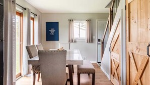 Een eethoek met een tafel, stoelen en een bordje aan de muur.