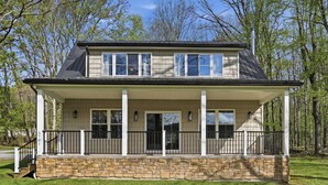 A two-story house with a stone foundation, a covered porch with black railings, and a chimney. - Doodle's Mountain Cape - Raystown Lake - Aunt Susie's (James Creek)