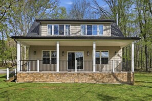 A two-story house with a stone foundation, a covered porch with black railings, and a chimney. - Doodle's Mountain Cape - Raystown Lake - Aunt Susie's (James Creek)
