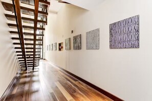 A hallway with wooden flooring, a staircase, and a series of patterned wall art. - Luxury DuPont Duplex/Anna Maria Residences 502 (Washington)