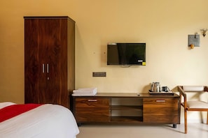 Ett hotellrum med en säng, en garderob i trä, ett skrivbord med en tv och en stol.