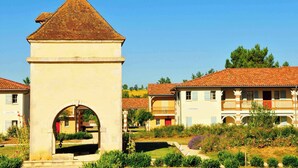 Um edifício tradicional com uma torre, um arco e um pátio com plantas.