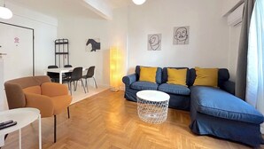 Ett modernt vardagsrum med en soffa, ett soffbord och en matplats med stolar och ett bord.
