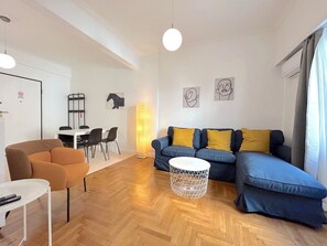 Ein modernes Wohnzimmer mit einer Couch, einem Couchtisch und einem Essbereich mit Stühlen und einem Tisch.