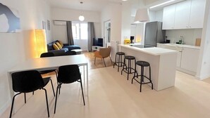 En modern lägenhet med matplats, kök och vardagsrum.