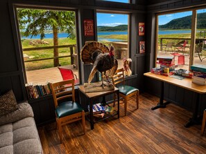 Una stanza accogliente con una grande finestra vista lago, un tavolo in legno con giochi da tavolo e una libreria piena di libri.