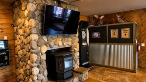 A stone fireplace with a TV, a dartboard, and a clock. - Room With Scenic Lake And Mountain Side Views (Panguitch)