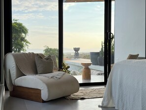 A modern bedroom with a sofa, a bed, and a view of the outdoors.