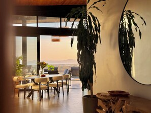 A modern dining area with a view of the mountains, a large potted plant, and a unique wooden table centerpiece. - Luxury villa with an ocean view near Playa Venao (Cañas)
