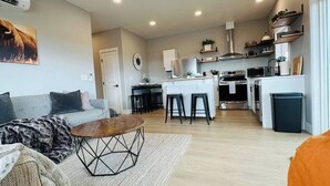 Uma sala de estar moderna com sofá, mesa de centro e cozinha ao fundo.