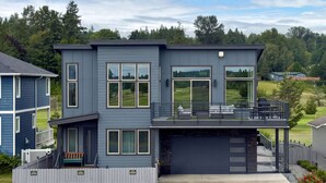 Ett modernt hus i två våningar med garage, stora fönster och en balkong.