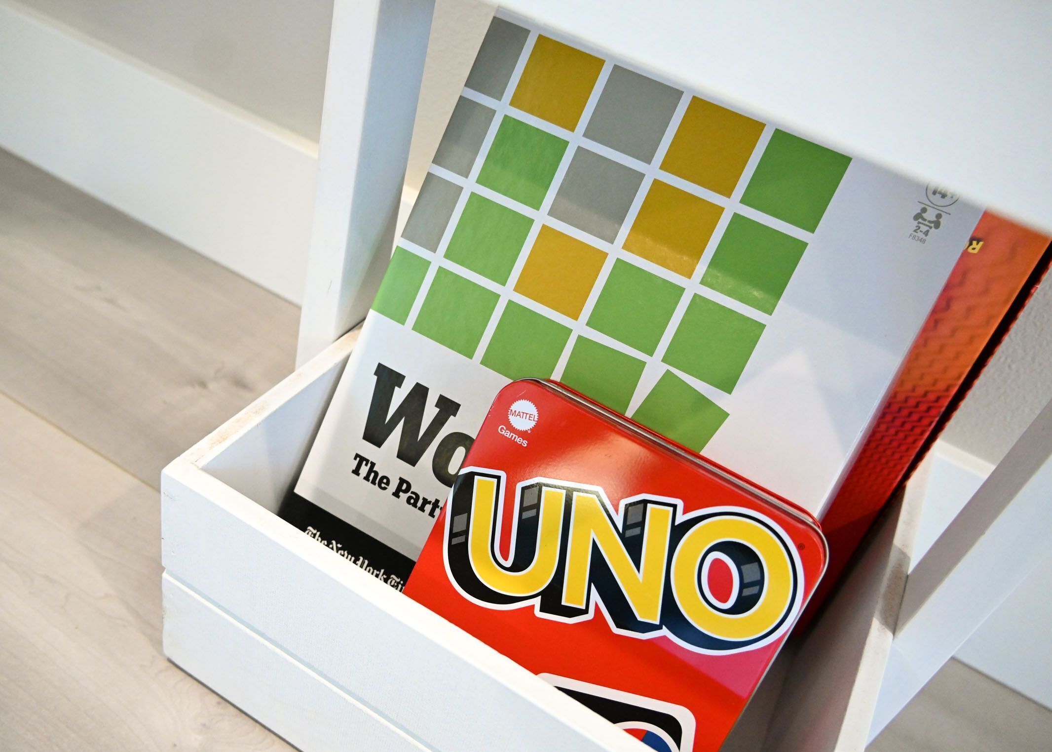 Eine weiße Schublade mit einer Spielbox mit dem Aufdruck 'UNO' und einer Karte mit der Aufschrift 'Gewinner – Das Partyspiel'.