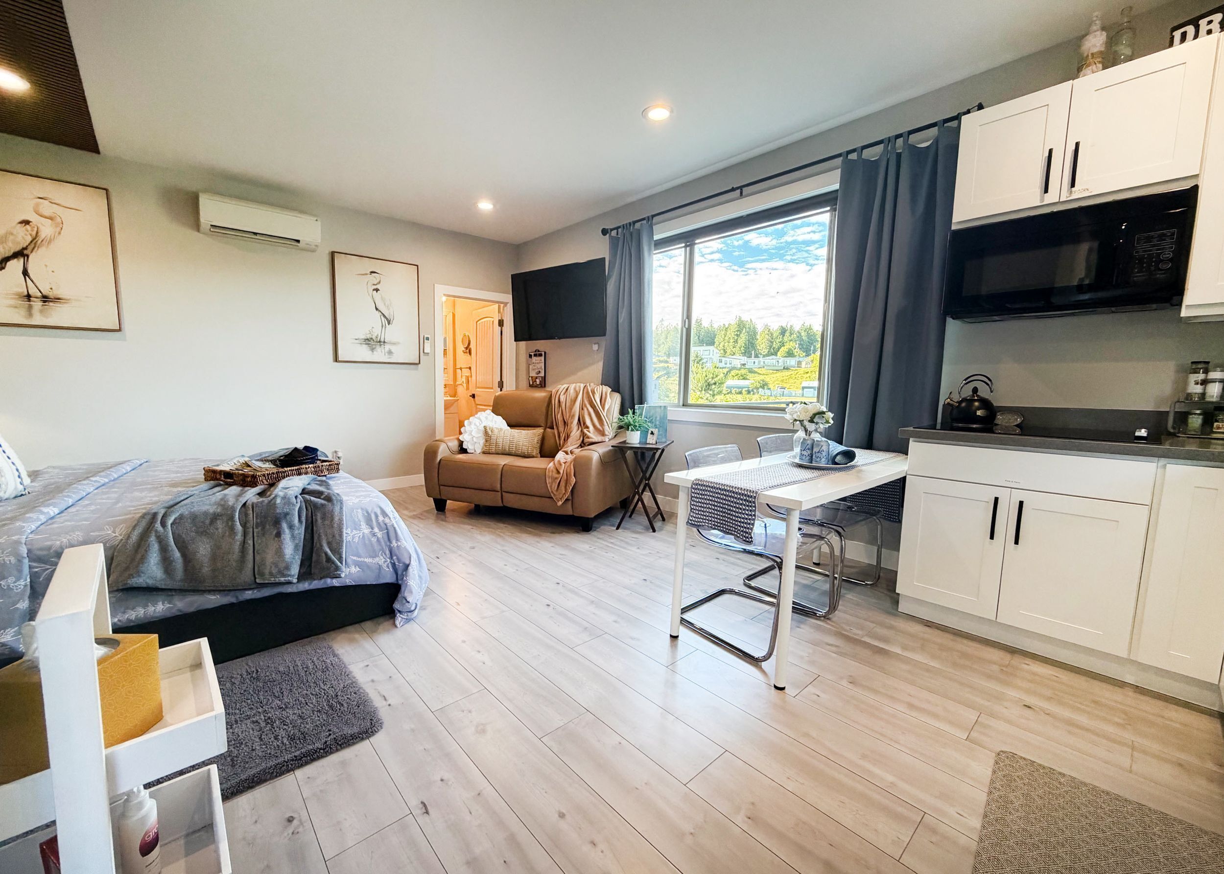 A modern room with a bed, a sofa, a dining table, and a kitchen area.