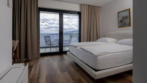 Et soveværelse med en stor seng, havudsigt og en balkon med stole.