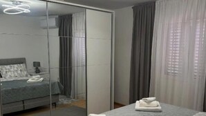 Makuuhuone, jossa on sänky, peili, yöpöytä ja ikkuna, jossa on verhot.