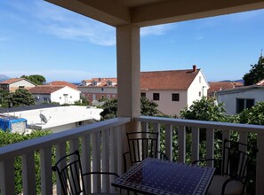 A balcony with a table and chairs, overlooking a residential area with houses and a clear sky. - One Bedroom Apartment with Balcony ( B ) (Orebic)