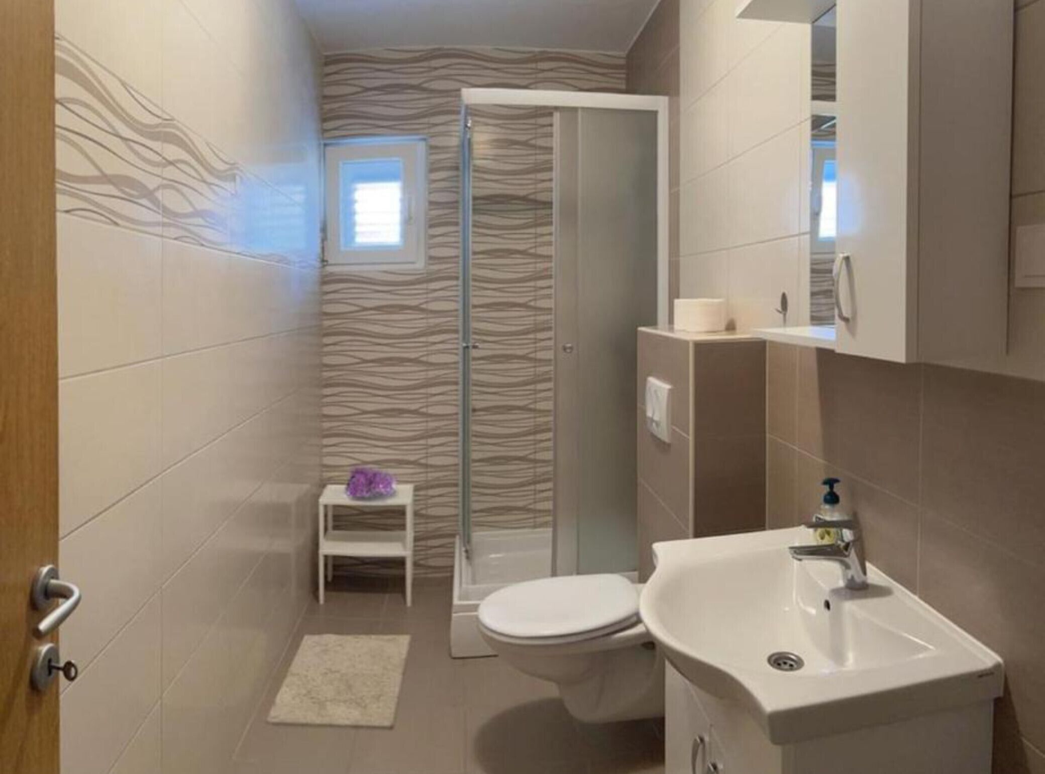 Une salle de bain équipée d’une douche, de toilettes, d’un lavabo et d’un petit marchepied.