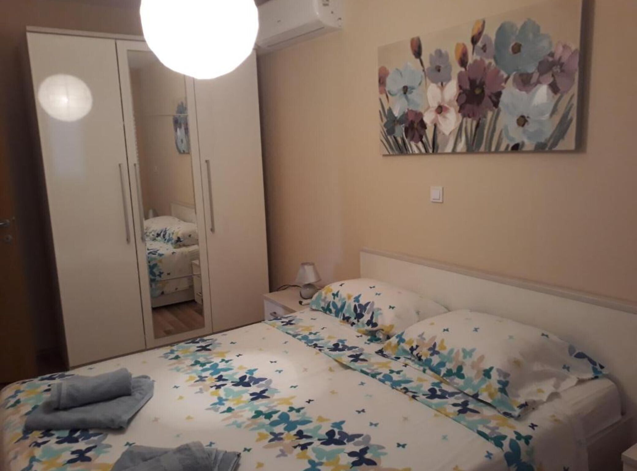 A bedroom with a bed, a wardrobe, a nightstand, and a painting on the wall.