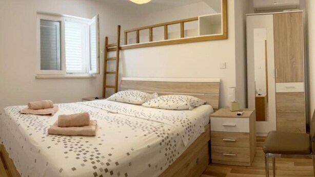 Et soveværelse med køjeseng, et natbord, en stol, et klædeskab og en hængende lampe.
