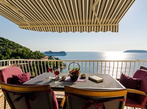 A terrace with a view of the sea, a table with a bottle of red wine, and a book. - One Bedroom Apartment with Terrace (Jezera)