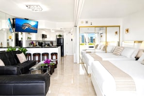 Habitación de hotel moderna con una cama grande, un sofá, un comedor y vistas a la ciudad.