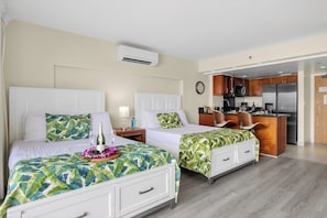 Ein Hotelzimmer mit zwei Betten, einer Küchenzeile und einer Klimaanlage.