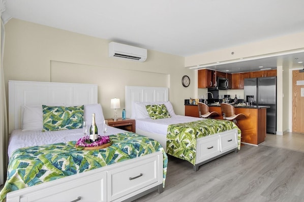 A hotel room with two beds, a kitchenette, and an air conditioning unit.