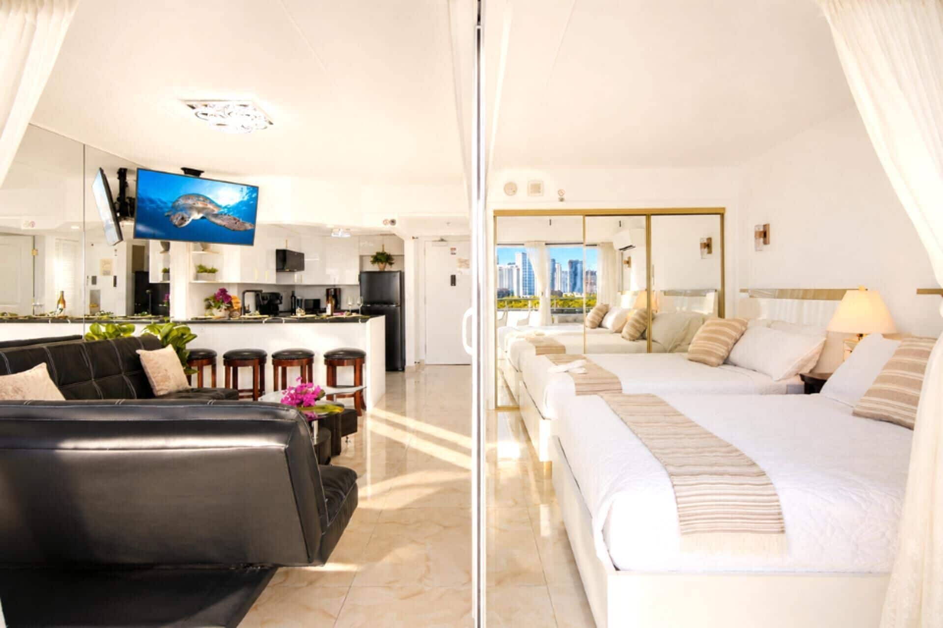 Una habitación de hotel moderna con sofá, cama, zona de cocina y televisor.